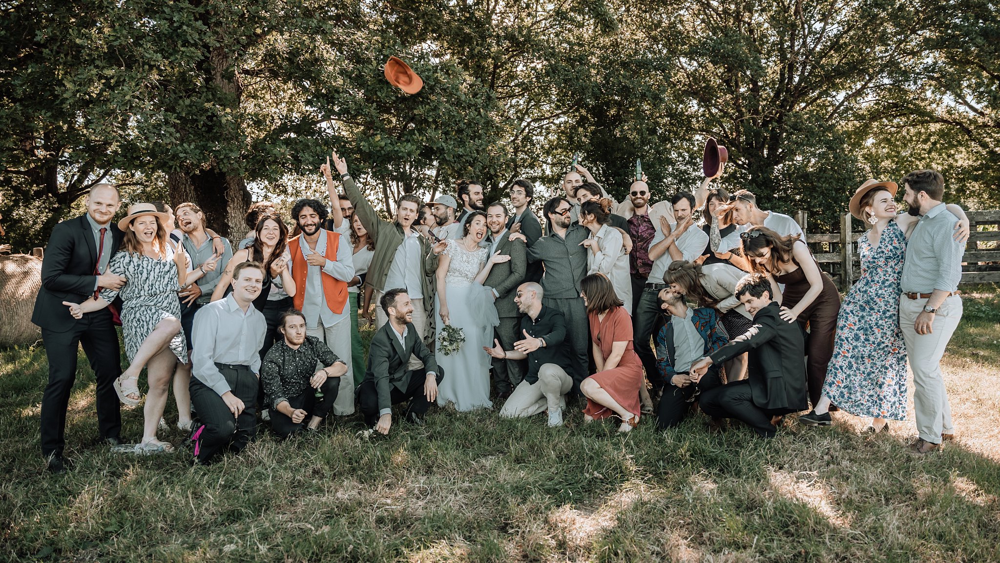photo de groupe où les gens jetent leurs chapeau,Un reportage photo mariage en Bretagne sur le thème champêtre et bohème