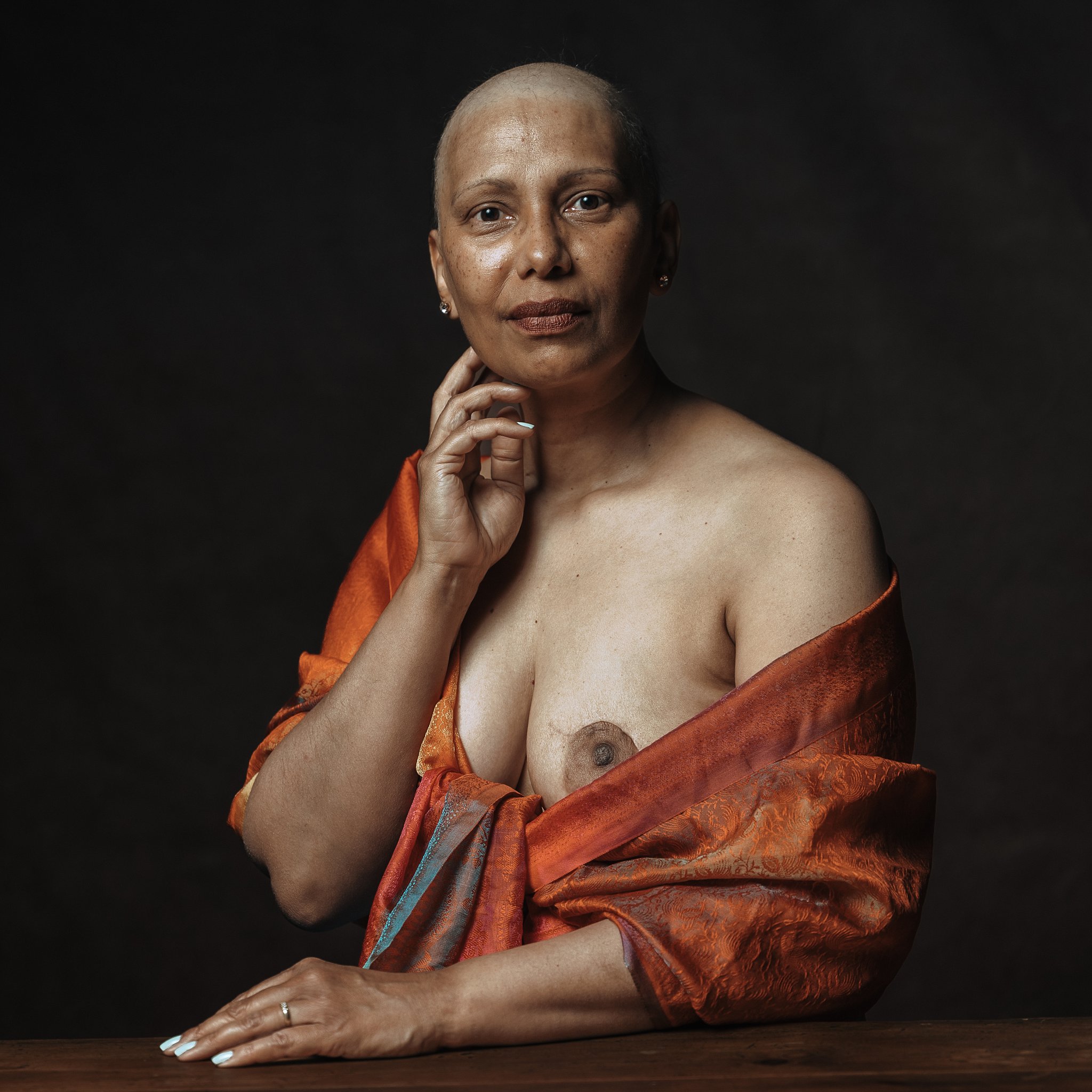 une femme regarde l'objectif fiere avec une main posé sur le cou, une femme qpose en s'amusant, seance photo pour lutter contre le cancer du sein