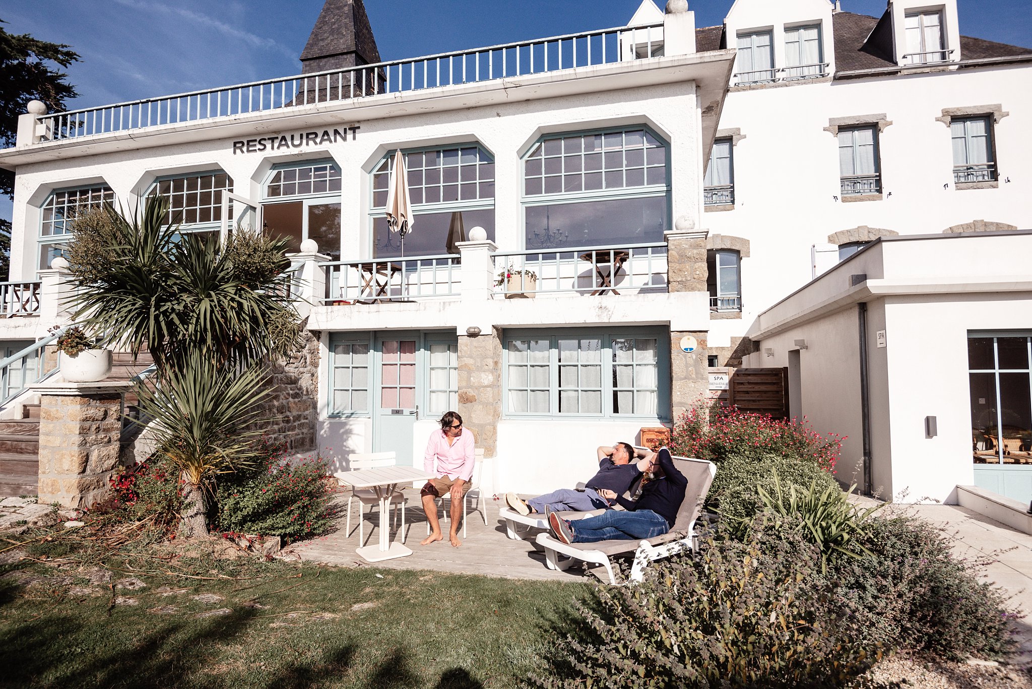 trois invités discutent au soleil devant l'hotel tumulus à carnac, Un sublime mariage à Carnac pour G & Y