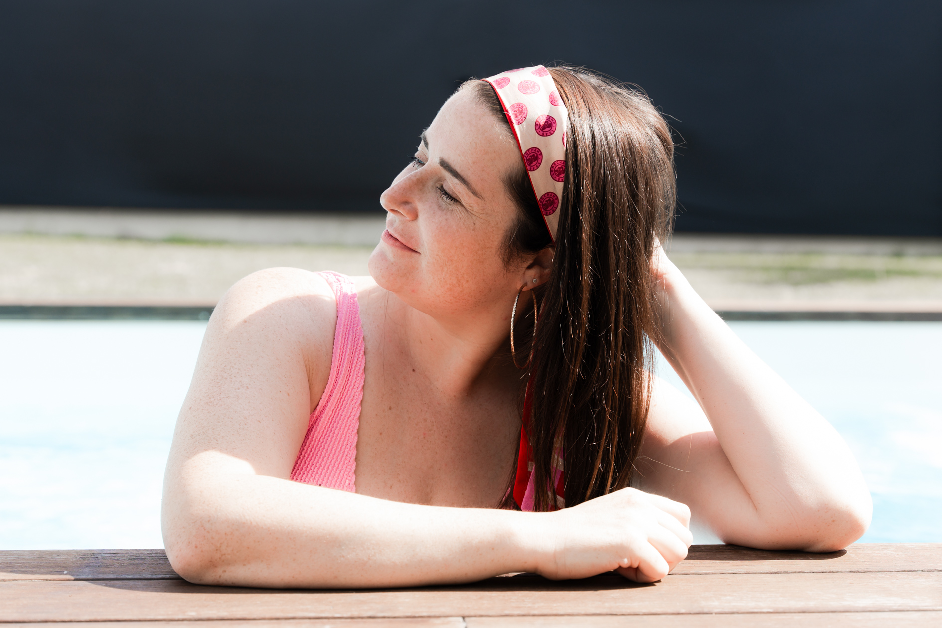 portrait d'une femme qui a le cancer du sein qui pose dans sa piscine lors d'une séance photo à domicile.